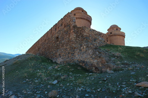 towers of the medieval spanish castle La Calahorra behind the outer wall, Granada, Spain photo