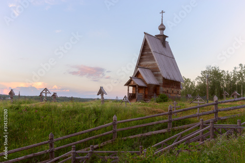 An old wooden Church stands on top of a hill. The Church is illuminated by the rays of the setting sun. Ples, Ivanovo Region, Russia.