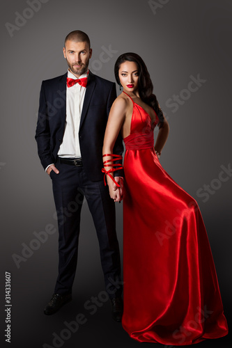 Fotografie Fashion Couple, Woman Red Dress and Man in Black Suit, Hands Bounded, Love Conce