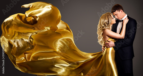 Obraz na plátně Couple, Fashion Woman in Golden Silk Fluttering Dress Kissing Elegant Man, Valen