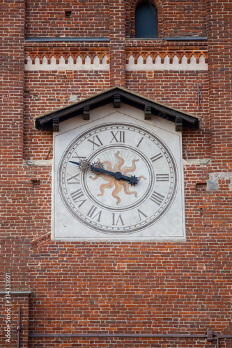 ancient clock on medieval red brick tower, Italy