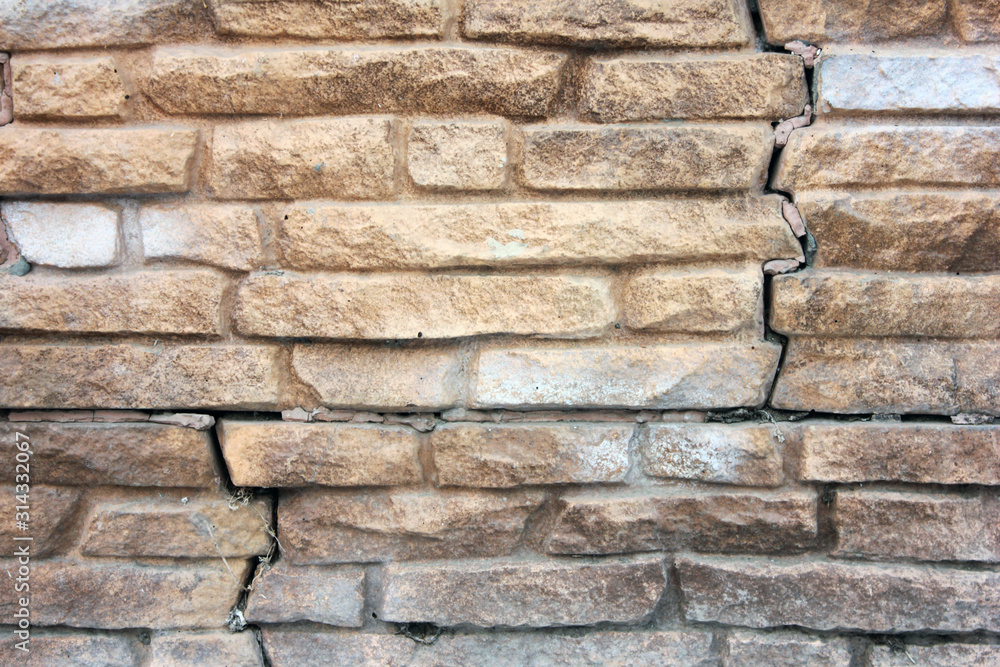 The background of the cracked brick wall in light orange or brown tone. Close up of old brick wall vintage texture with fissure. The background of the cracked brick wall in light orange or brown tone. Close up of old brick wall vintage texture with fissure.