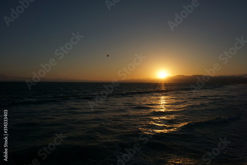 Sun going down behind a surfer and Paraglider off the beaches of Santa Monica  California