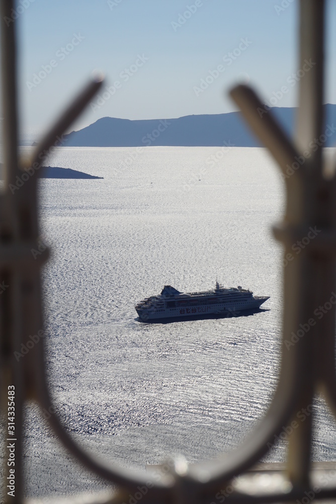 Fototapeta premium Cruise ship passing by the mountain side of Santorini, Greece in the open ocean