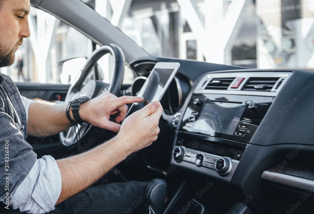 Young handsome driver man with smartphone serfing internet and drink black coffee