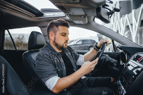 Young handsome driver man with smartphone serfing internet and drink black coffee © klepach