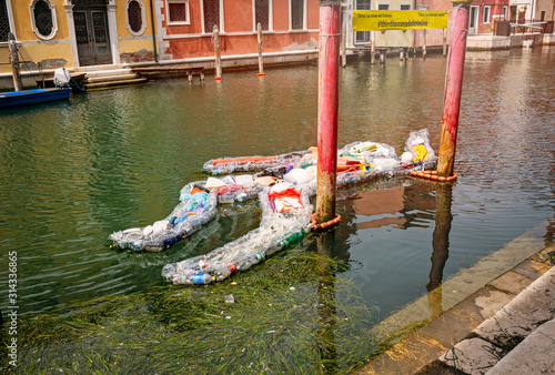 Chioggia, Venice, Veneto, Italy August 1, 2019. Exposition A man of plastic bottles is located on a canal in Chioggia