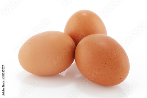 Three brown chicken eggs on a white background
