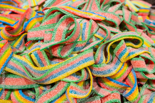 A large pile of interwoven marmalade strips in a supermarket. Delicious striped ribbons sprinkled with white sugar. Bright pastry background.