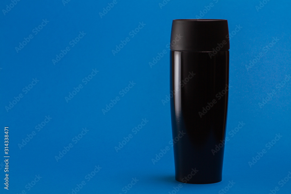 one black thermal bottle shaker for sports nutrition on a blue background. one black thermal bottle shaker for sports nutrition on a blue background.