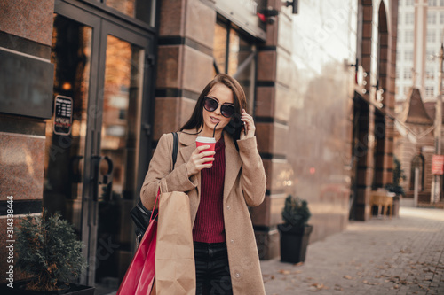 Young pretty woman in coat with shopping bags, cup of black coffee and smartphone © klepach