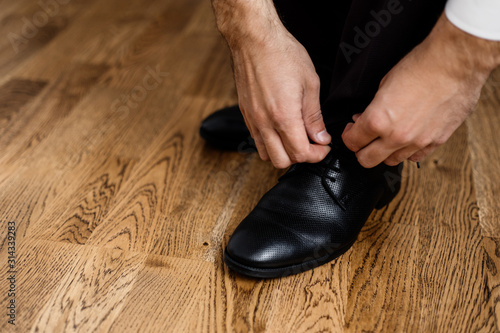 Man is tying the laces on the wooden floor