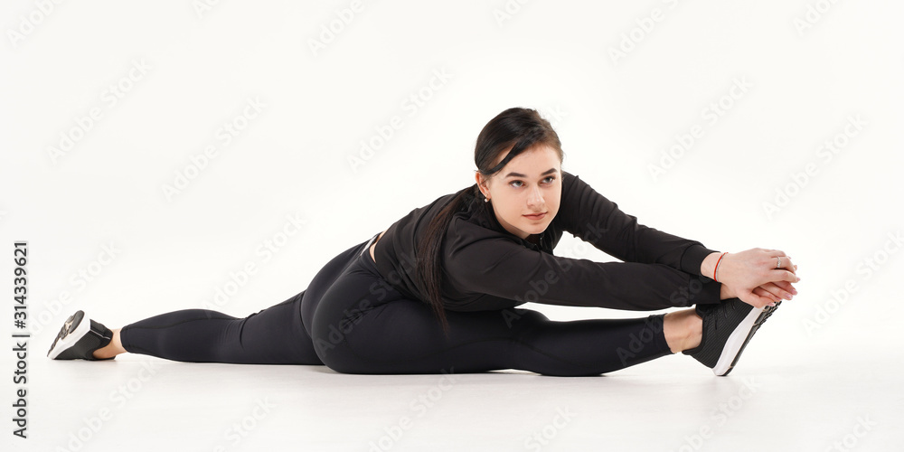 Foto de Young girl doing stretching gymnastic exercises sitting on