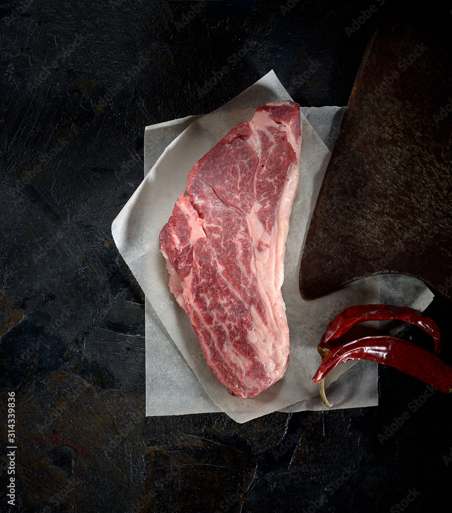 fresh raw marbled beef steak on parchment paper on a dark background