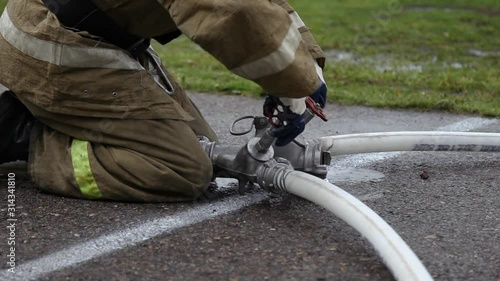 Close up of a fireman with hose splitter and fire hoses, unscrews the valves
