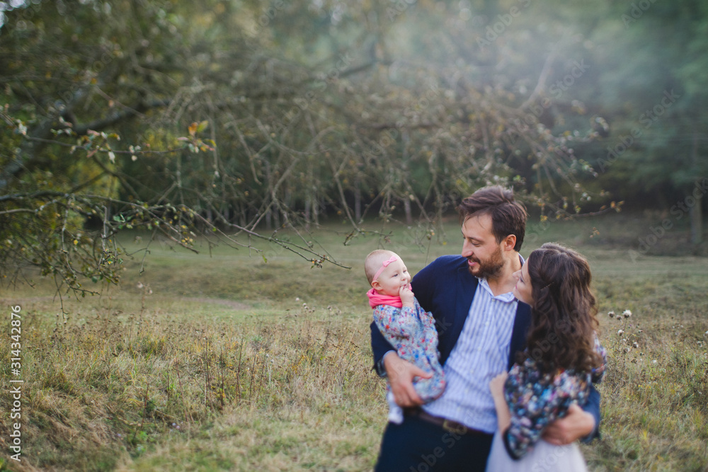 Young happy caucasian couple with little baby girl. Parents and daughter walking and having fun together. Mother and father play with child outdoors. Family, parenthood, childhood, happiness concept. Young happy caucasian couple with little baby girl. Parents and daughter walking and having fun together. Mother and father play with child outdoors. Family, parenthood, childhood, happiness concept.