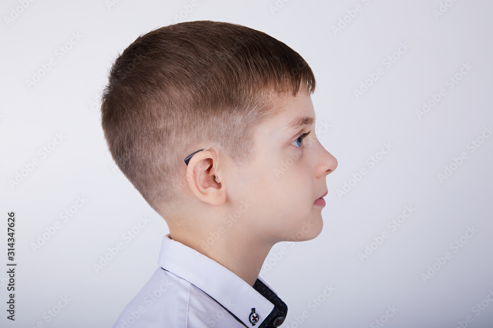 Young boy wearing a hearing aid. Studio shot. Young boy wearing a hearing aid. Studio shot.