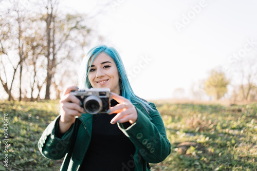 Girl looking into a camera while holding photo camera © Synergic Works OÜ