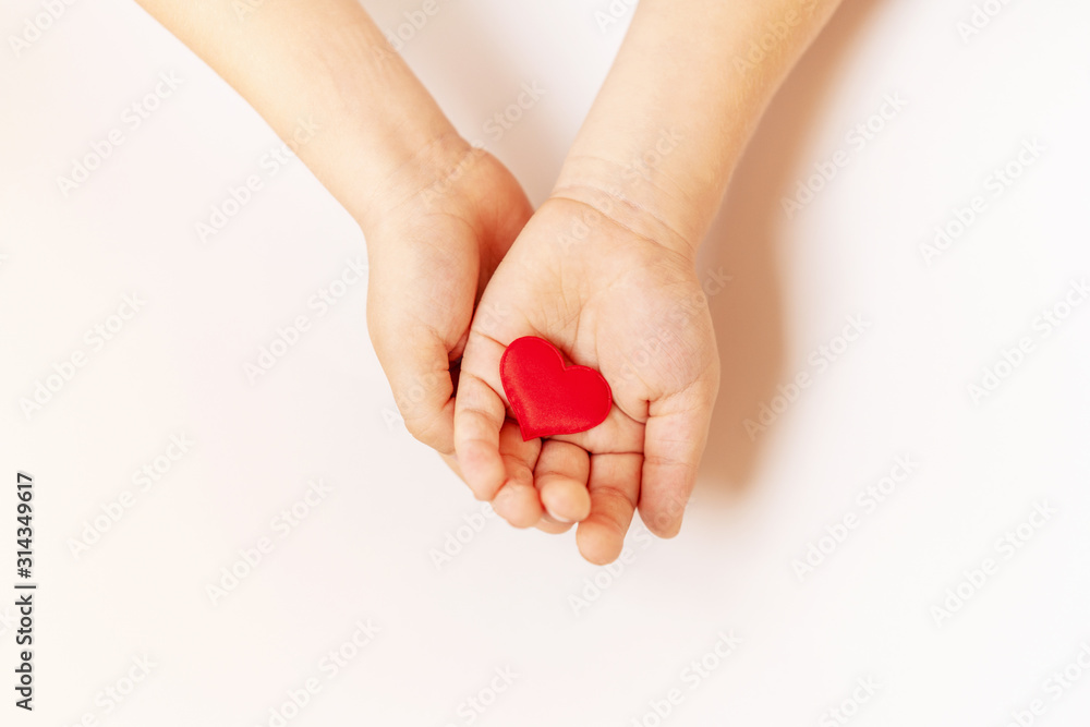 Close up of child hands holding red hearton white background - people, love, charity and family concept Close up of child hands holding red hearton white background - people, love, charity and family concept
