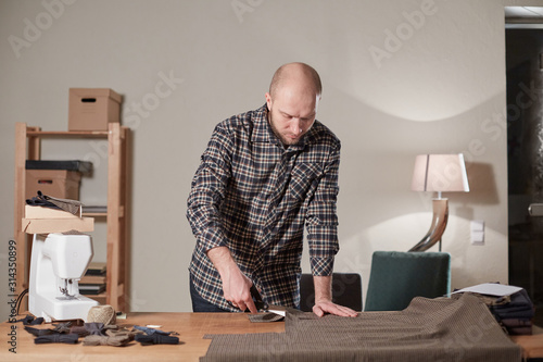 Tailor cutting wool fabric. the line pattern. Craftsman Makes rectangular blanks for Bow ties of woolen fabric. Work with sewing machine in a textile studio.