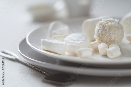 Various white candies, marshmallows and a spoon with peanut butter