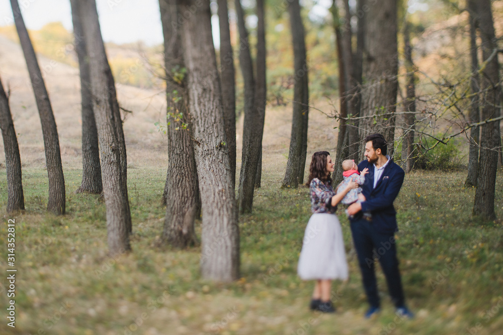 Young happy caucasian couple with little baby girl. Parents and daughter walking and having fun together. Mother and father play with child outdoors. Family, parenthood, childhood, happiness concept. Young happy caucasian couple with little baby girl. Parents and daughter walking and having fun together. Mother and father play with child outdoors. Family, parenthood, childhood, happiness concept.