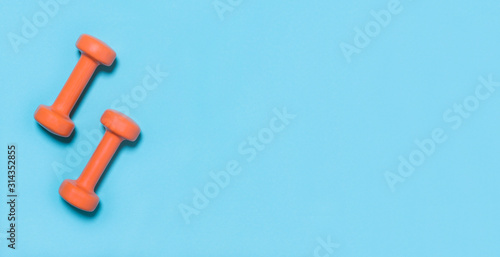 Orangedumbbells isolated on blue background © Augustas Cetkauskas