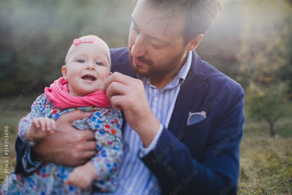 Fototapeta premium Young happy caucasian man with little baby girl. Parent and daughter walking and having fun together. Father playing with child outdoors. Family, parenthood, childhood, happiness concept.