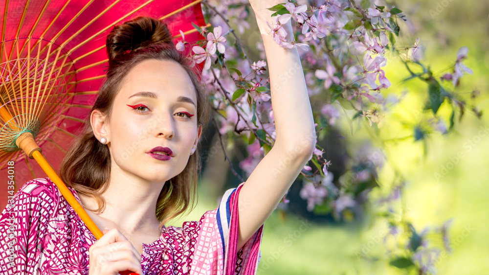 Japanese woman in kimono and with umbrella. Beauty Asian girl with a bright make-up art in green scenery park Japanese woman in kimono and with umbrella. Beauty Asian girl with a bright make-up art in green scenery park