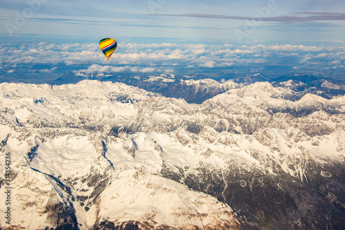 Luftaufnahme der schneebedeckten Alpen mit buntem Heißluftballon photo