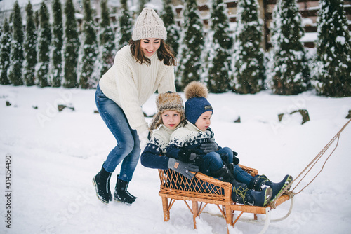 mom with two sons on a sleigh