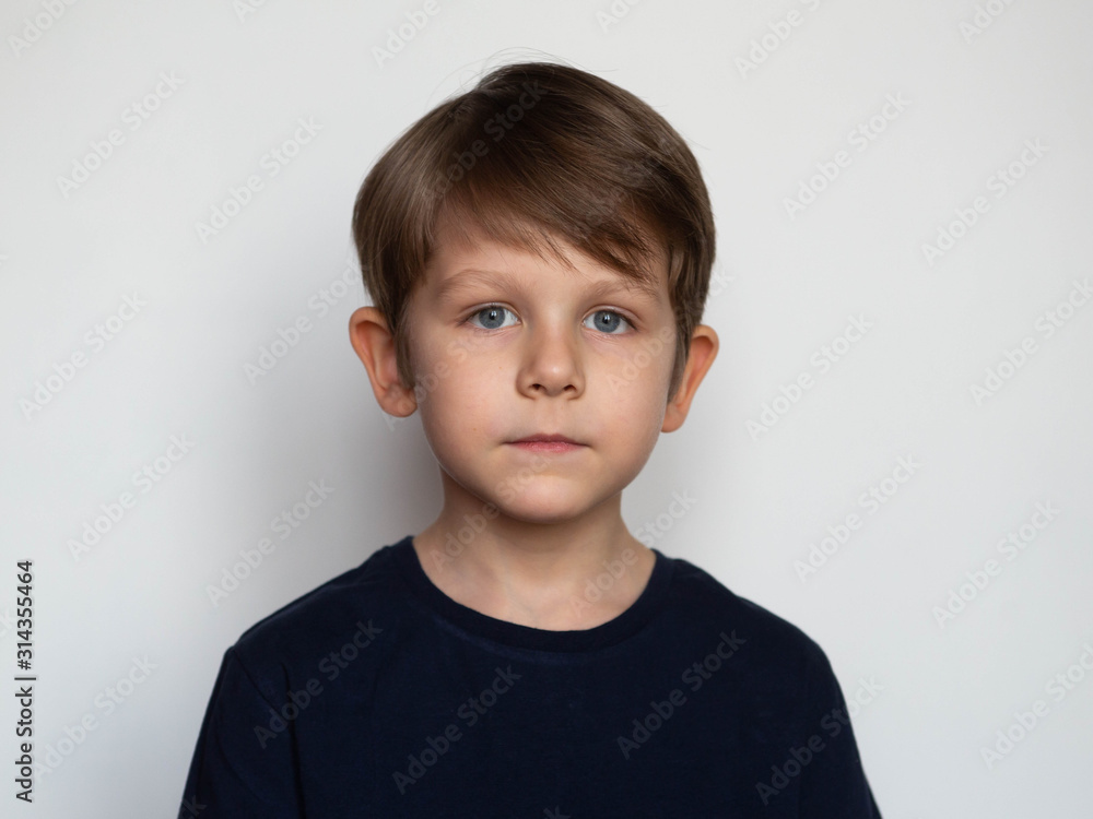 Portrait of a serious little boy on a white background - obrazy, fototapety, plakaty 