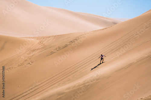 silhouette of man practice sandboarding in the desert of Peru.