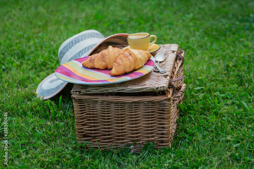 Picnic at the park on the grass: wicker basket, fresh croissants and coffee