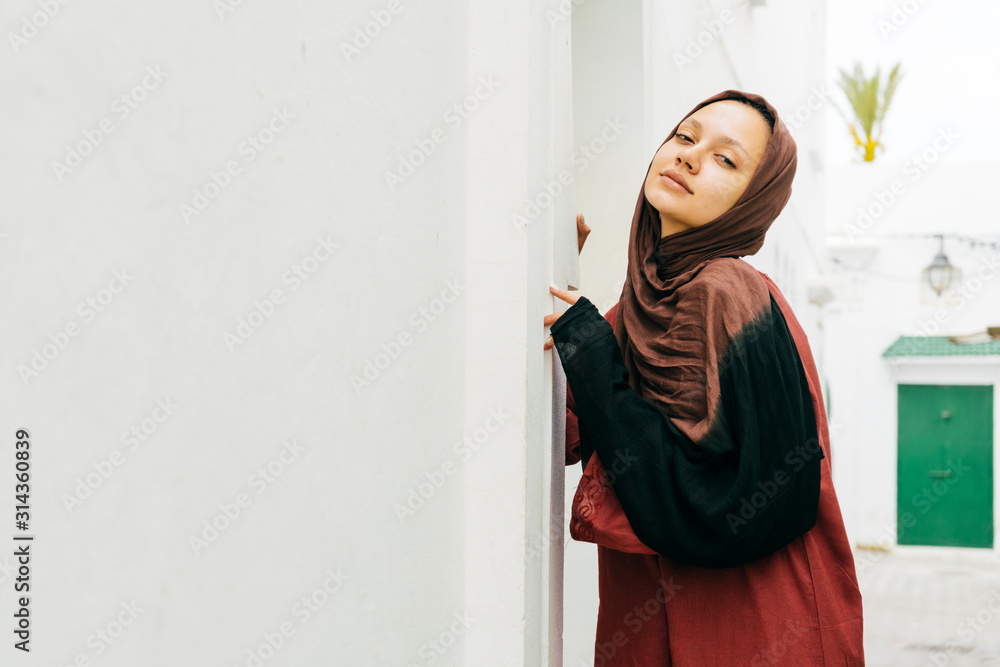 muslim woman leaning her head back painfully, leaned her hands against the wall of the house