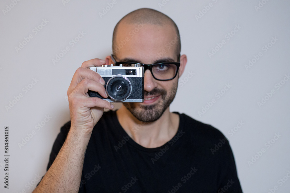Caucasian smiling boy with beard takes a photo picture with a vintage retro 35mm film camera Caucasian smiling boy with beard takes a photo picture with a vintage retro 35mm film camera