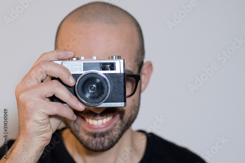 Caucasian boy with beard uses a vintage retro 35mm film camera 