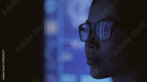 The businesswoman looking on the blue screen in the dark lab