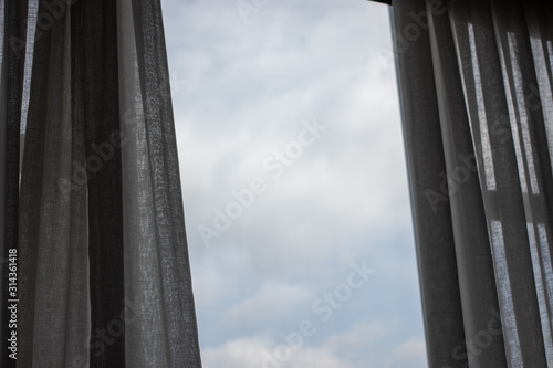 window with sky and clouds between curtains