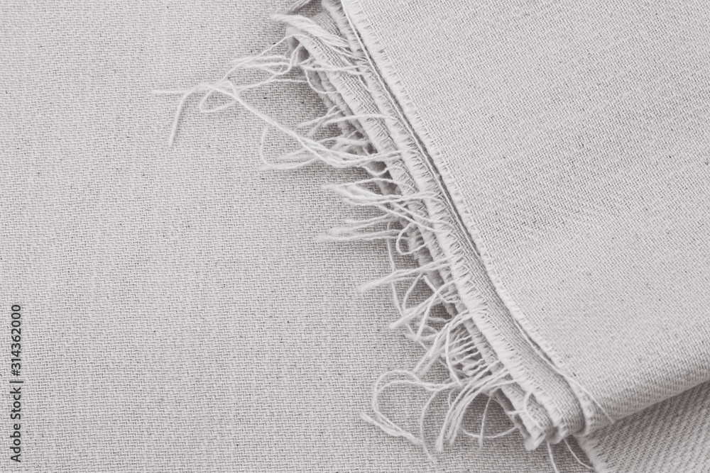 Folded twill fabric in light gray; soft grey material pressed with frayed  edge visible Stock Photo