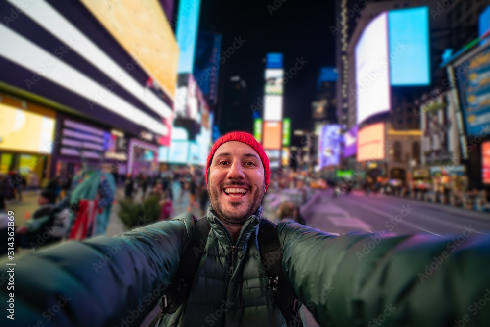 smiling young man taking a selfie with his smartphone on Times Square, New York. tourism in united states of America smiling young man taking a selfie with his smartphone on Times Square, New York. tourism in united states of America