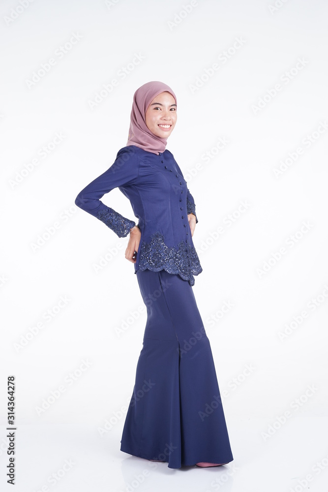 A beautiful Muslim female model wearing a dark blue modern kebaya with hijab, an Asian Muslim traditional dress isolated on white background. Eidul fitri fashion and lifestyle portrait concept. A beautiful Muslim female model wearing a dark blue modern kebaya with hijab, an Asian Muslim traditional dress isolated on white background. Eidul fitri fashion and lifestyle portrait concept.