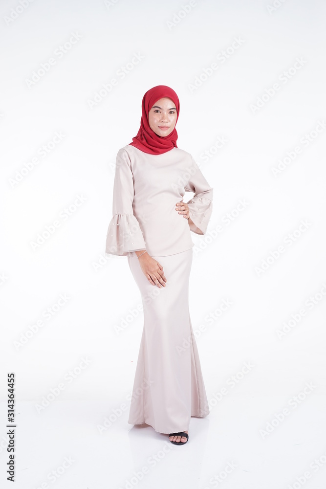 Attractive Muslim female model wearing a cream colored modern kebaya with red hijab, an Asian Muslim traditional dress isolated on white background. Eidul fitri fashion and lifestyle portrait concept. Attractive Muslim female model wearing a cream colored modern kebaya with red hijab, an Asian Muslim traditional dress isolated on white background. Eidul fitri fashion and lifestyle portrait concept.