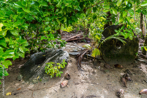Foto Two giant prehistoric megalithic stone coins or money rai, lying in the sand hidden under trees overgrown in jungle