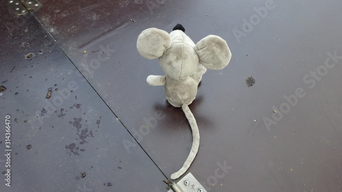 The soft toy rat sits on the well lid. View from the back.