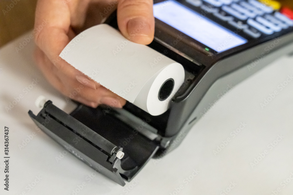 Pos terminal paper roll being replaced by a woman holding it in hand Pos terminal paper roll being replaced by a woman holding it in hand