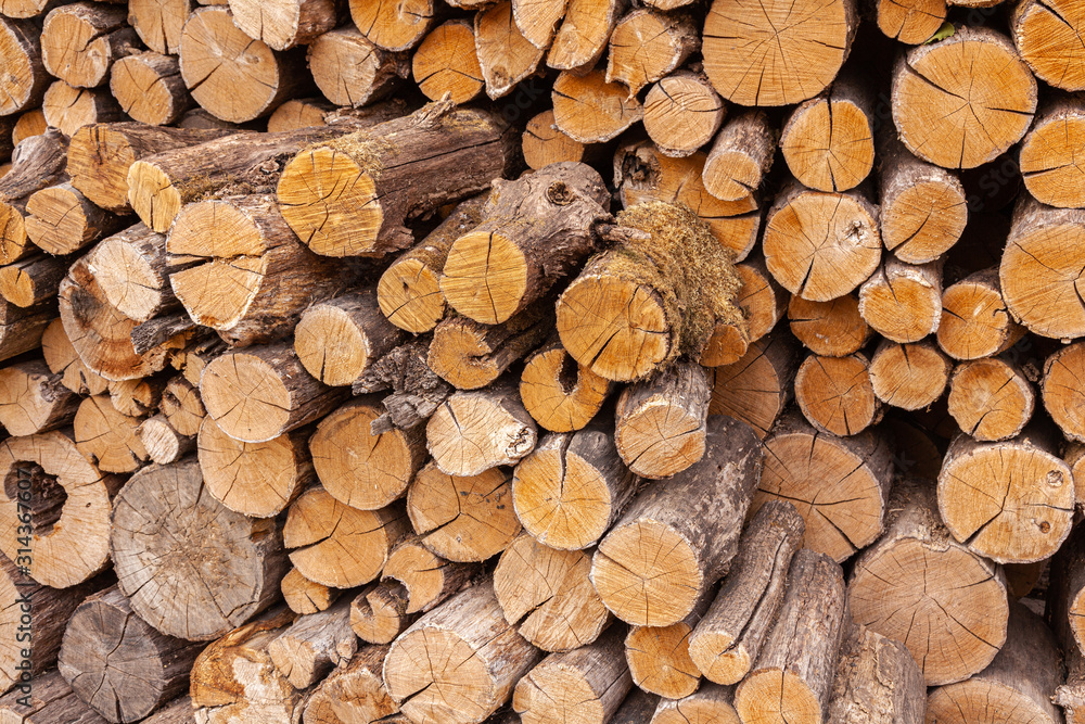 Natural wood background. Dry oak firewood stacked in a pile, a whole log for winter fireplace heating. Organic fuel. Natural wood background. Dry oak firewood stacked in a pile, a whole log for winter fireplace heating. Organic fuel.