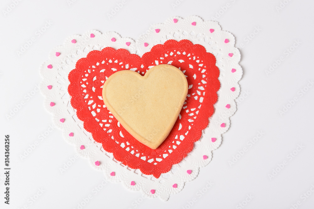 Valentines Day Concept: A heart shaped sugar cookie on heart shaped doilies.