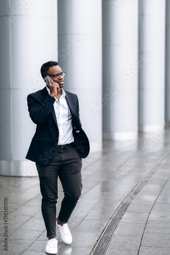 Young stylish african american student talking on the phone and smiling, near the university