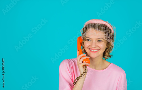 Smiling woman in pink dress with telephone handset. Happy woman holds handset. Pretty woman talking at retro handset. Girl talking on landline phone. Communication. Young woman talking on retro phone.